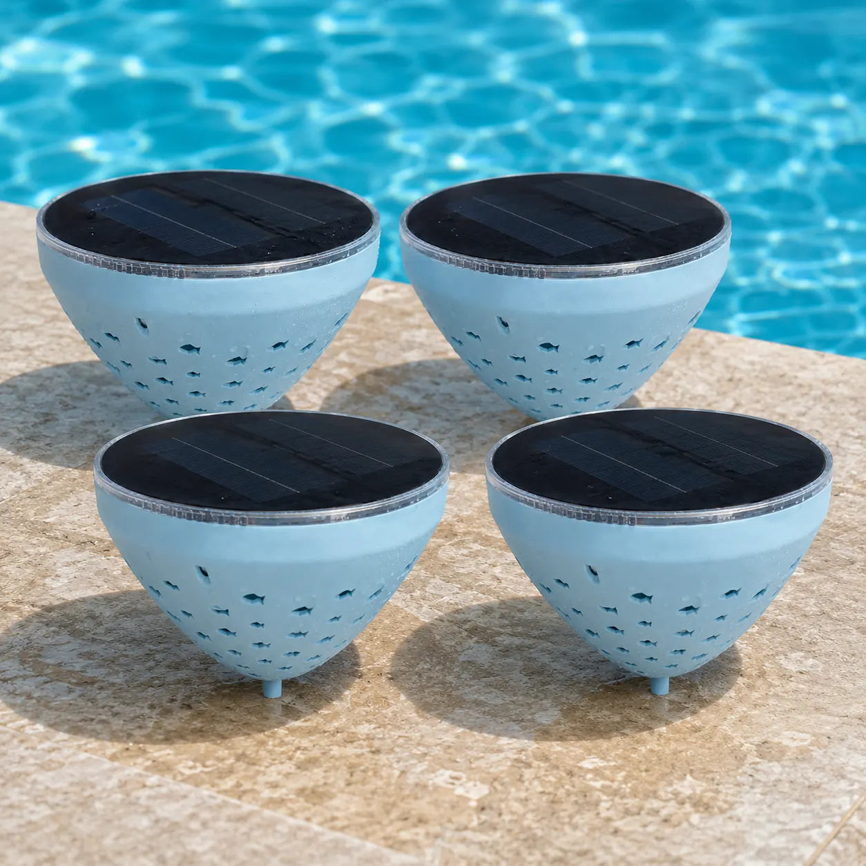 Four solar floating pool lights beside a pool in daylight